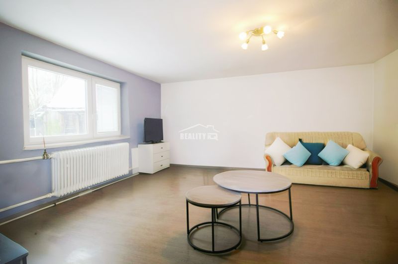 Living room with a sofa, coffee tables, and wood-patterned flooring in a family house.