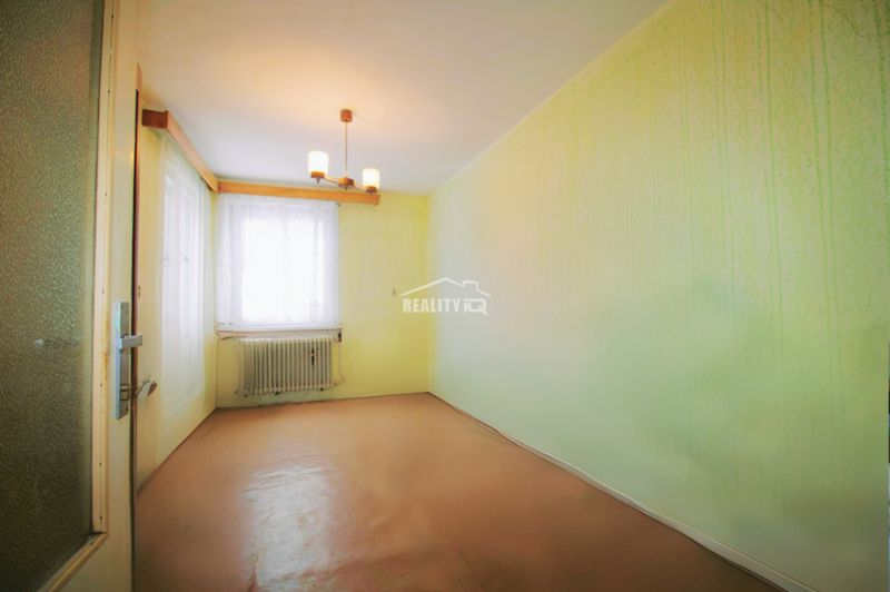 A room in a family house with a simple chandelier and a window radiator.