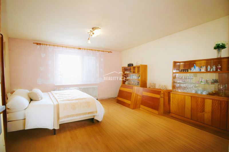 Bedroom in a family house with wood-decor flooring, bed, furniture, window.