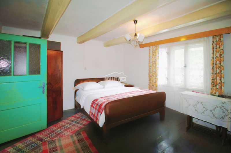 Rustic bedroom in a family house with green doors and wooden beams on the ceiling.