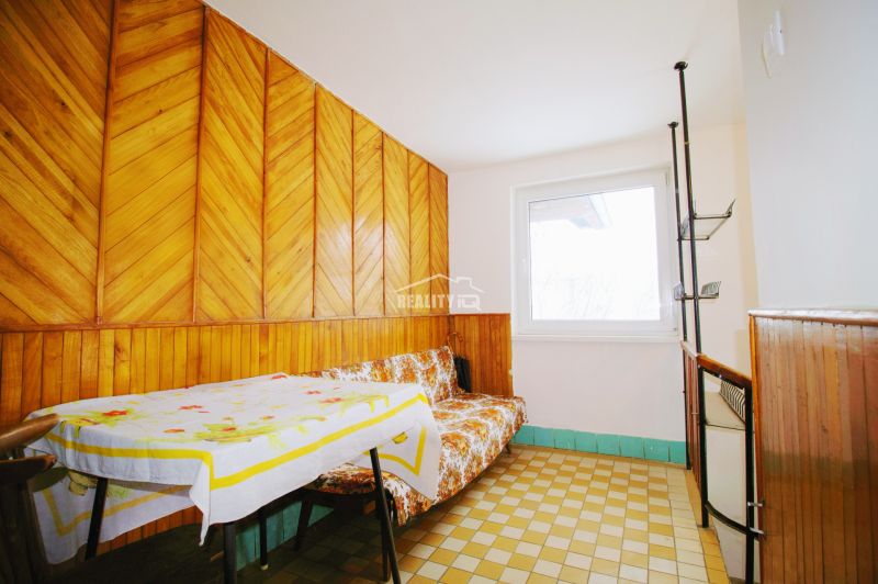 Interior of a family house with wooden paneling, a sofa, and a table with a tablecloth.