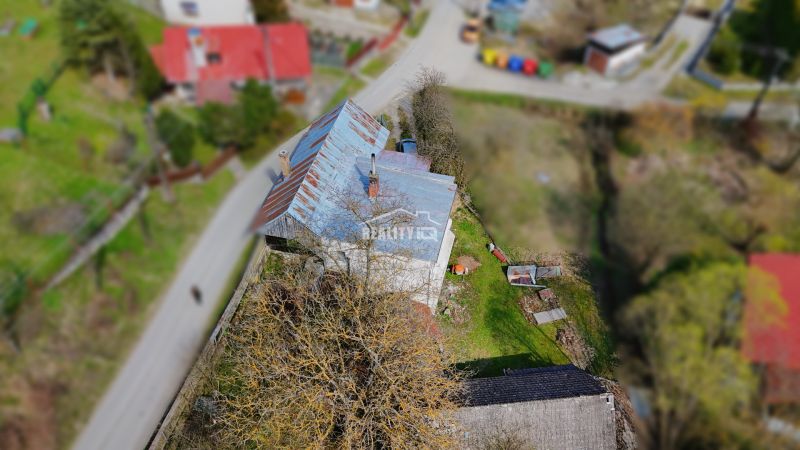 A family house in Petrovice with a metal roof and a garden, surrounded by greenery.