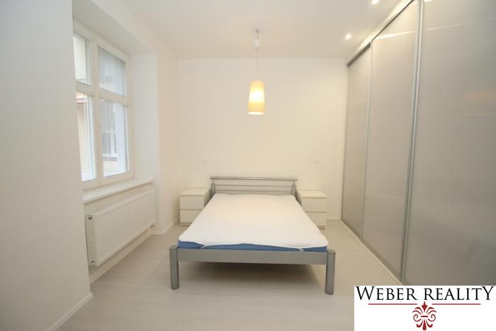 A bright bedroom in a 2-room apartment with a sliding wardrobe and central lighting.