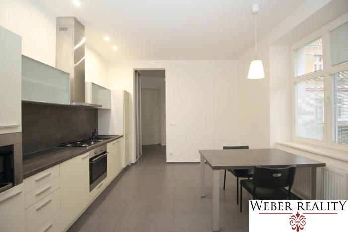 A kitchen in a 2-room apartment with a kitchen unit, dining table, and a large window.