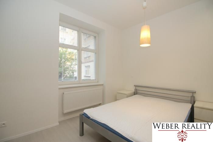 Bedroom in a 2-room apartment with a simple bed and a pendant light.