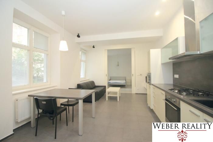 A kitchen with a dining area and a view into the bedroom in a 2-room apartment.