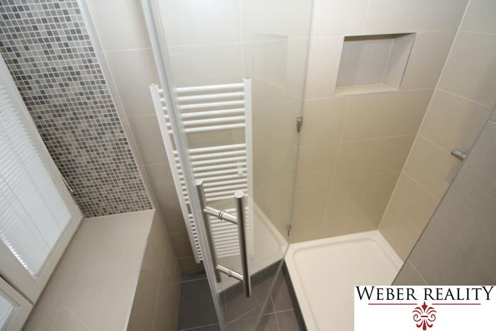A bathroom with a shower and light tiles in a 2-room apartment.