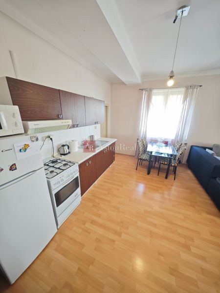 A kitchen in a 2-room apartment with a wooden decor floor and a dining area.