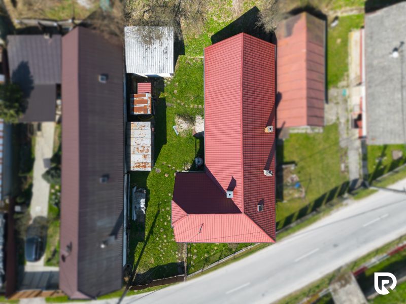 A family house in Dolná Poruba with a red roof and a garden surrounded by houses.