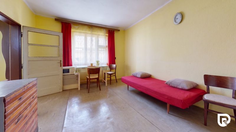 Yellow walls, a bed with a red throw, two chairs, a table in a family house.