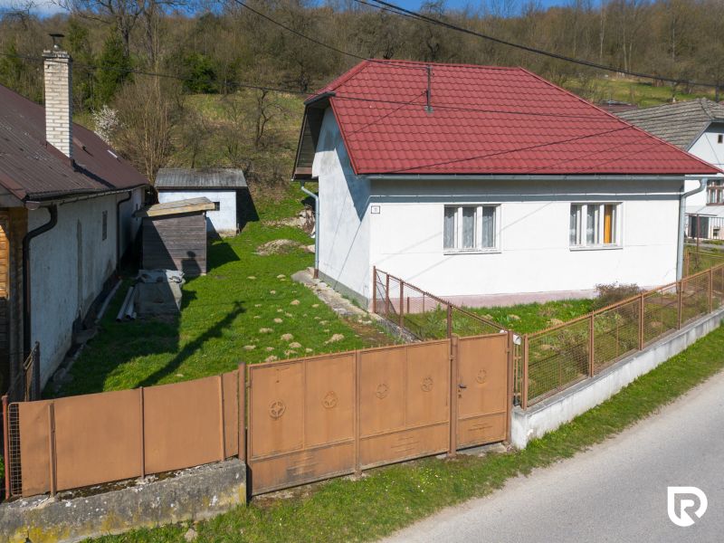A family house in Dolná Poruba on Dolná Poruba Street with a grassy yard and a metal gate.