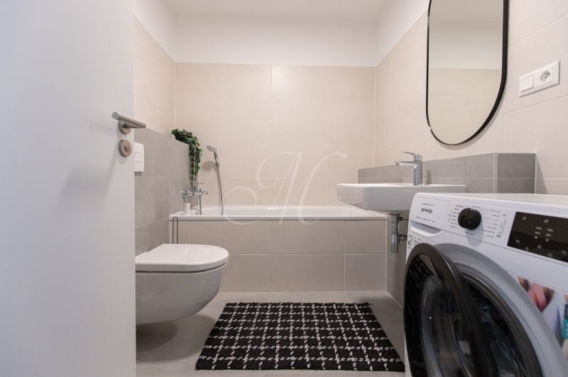Bathroom in a 2-room apartment with a bathtub, washing machine, and toilet.