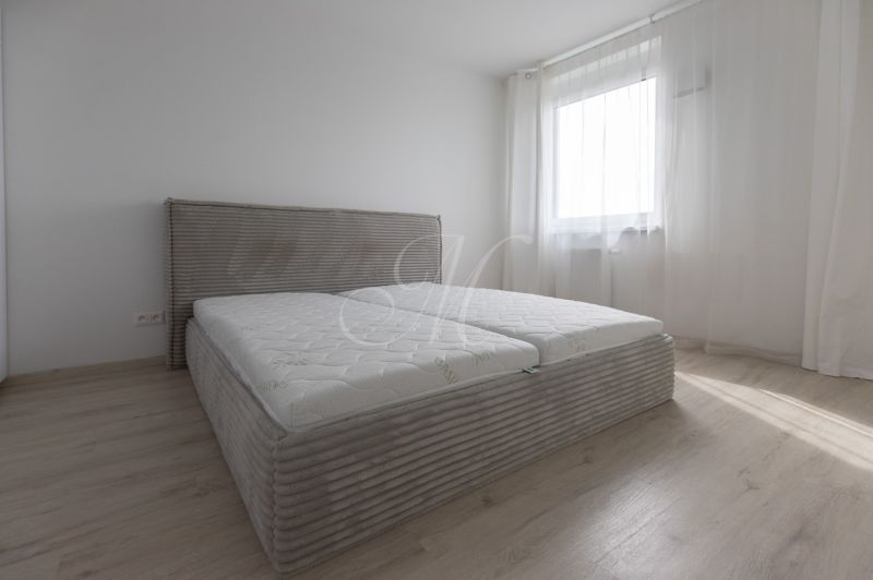 Bedroom with a bed and wooden decor flooring in a two-room apartment.