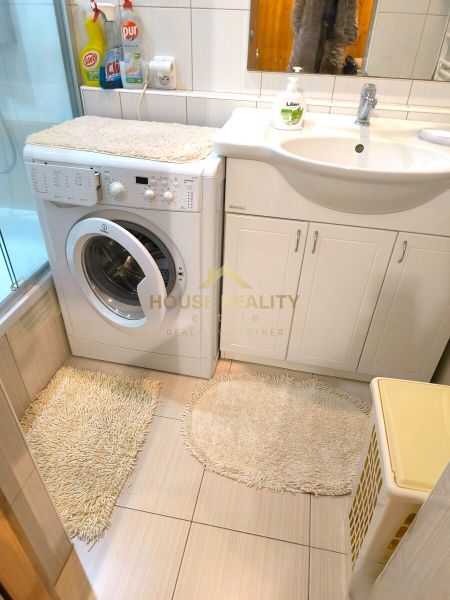 Bathroom with a shower, washing machine, and sink, ideal for a 3-room apartment.