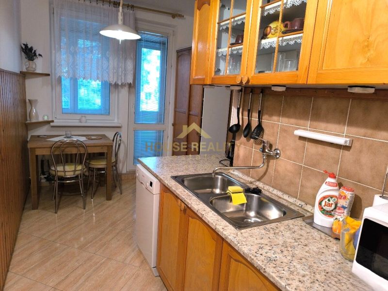 A kitchen in a 3-room apartment with a wooden decor floor and a dining table.