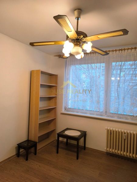 A room in a 3-room apartment with a wooden decor floor, a ceiling fan, and furniture.