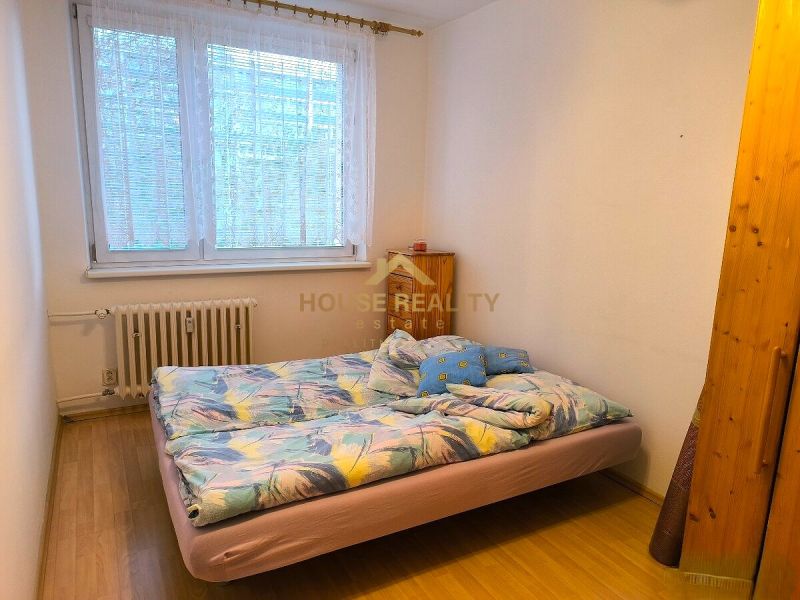 A bedroom with a bed and a wooden decor floor in a 3-room apartment.