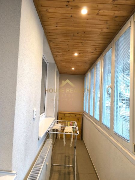 Glazed balcony with a wooden ceiling and a clothes dryer in a 3-room apartment.