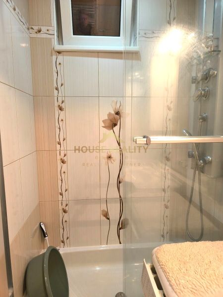 A bathroom with a shower and floral tiles in a 3-room apartment.