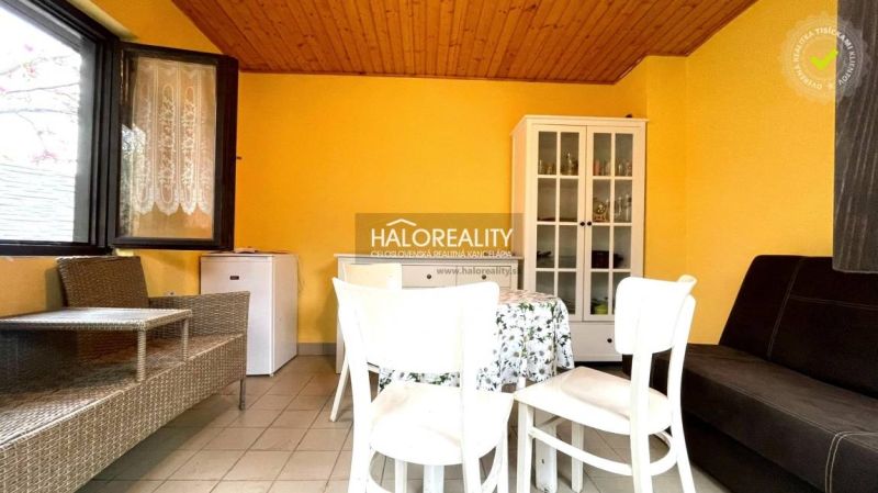 Interior of a garden with a white dresser, table, and wicker furniture, yellow walls.