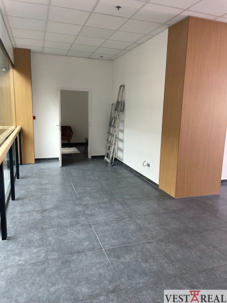 Interior of commercial spaces with dark tiles and simple walls, white ceiling structure.