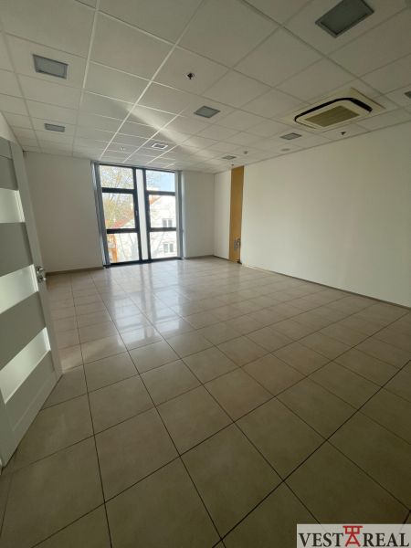 Empty commercial space with a large window, ceramic flooring, and air conditioning.