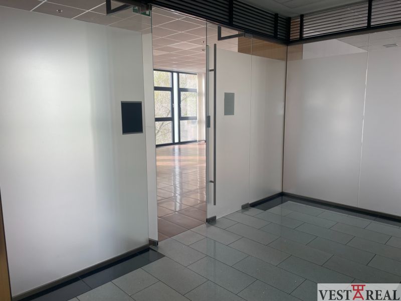 Glass walls and entrance in commercial premises with wood-patterned flooring.