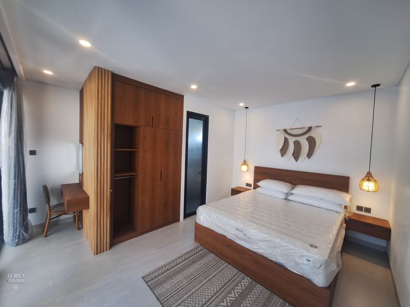 Bedroom of the villa with wood-patterned flooring, a wardrobe, and wall decoration.