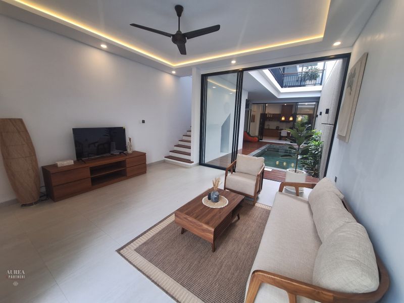 Living room in a villa with wood-patterned flooring, view of the pool.