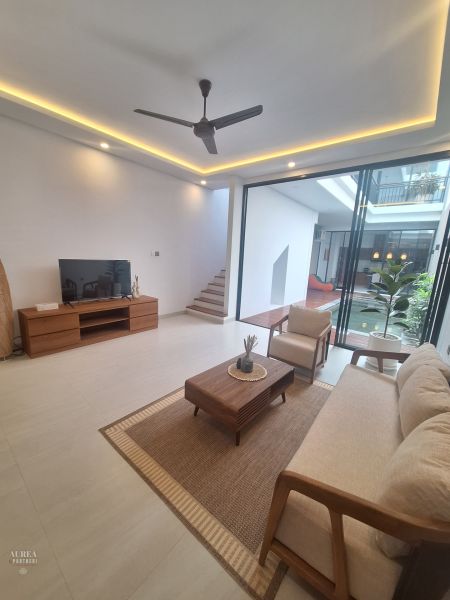 A bright living room of a villa with comfortable furniture and glass doors to the terrace.