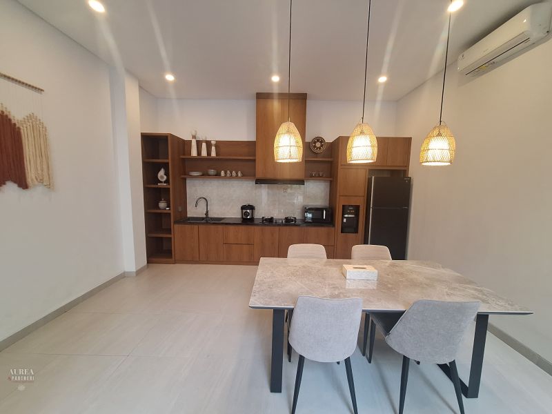 Dining area in a villa with a kitchen unit and pendant lamps.