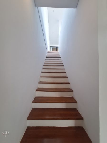 The staircase of the villa with a wooden decor floor and white walls.