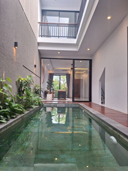 Villa in Bali with a pool and plants, terrace with wooden decor flooring.