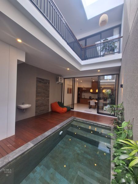 Interior of a villa with a pool, wooden floor decor, and comfortable seating.