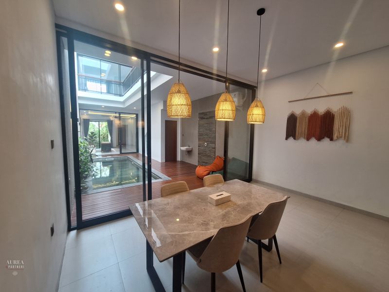Dining room in the villa with a view of the indoor pool and wall decoration.