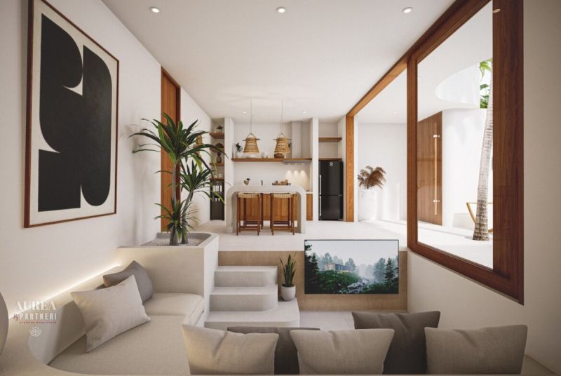 Interior of a villa with a kitchen and living area, decorated with plants and a painting.