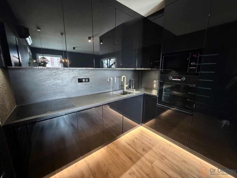 Black kitchen in a 2-room apartment with a wooden decor floor.