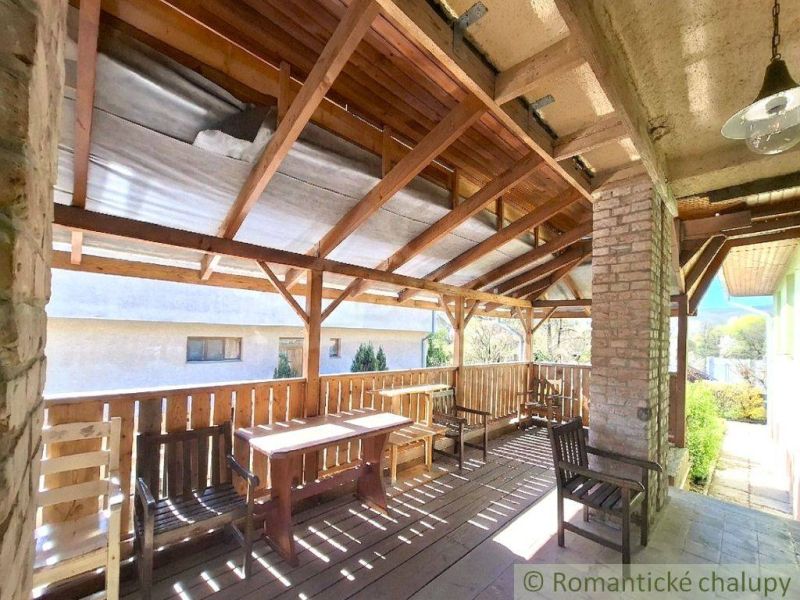 Covered terrace of a family house in Lupoč with wooden seating and a view of the garden.
