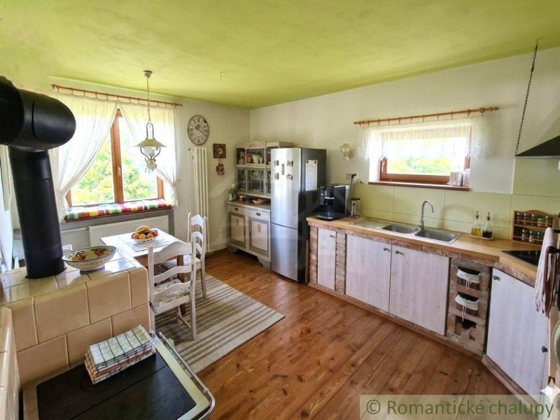 Rustic kitchen in a family house with a wood-patterned floor and a traditional stove.