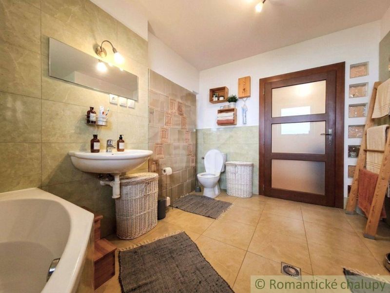 A bathroom in a family house with light tiles, a sink, and a bathtub.