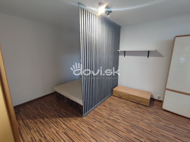 Bedroom in a studio apartment, wooden decor flooring, minimalist furnishings.
