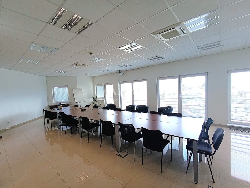 Spacious offices with a long table and many chairs, tiled floor.