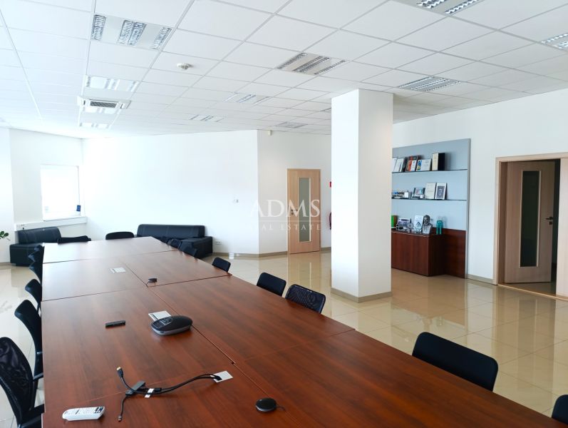 Offices with a long wooden table, floor with wooden decor, comfortable seating.