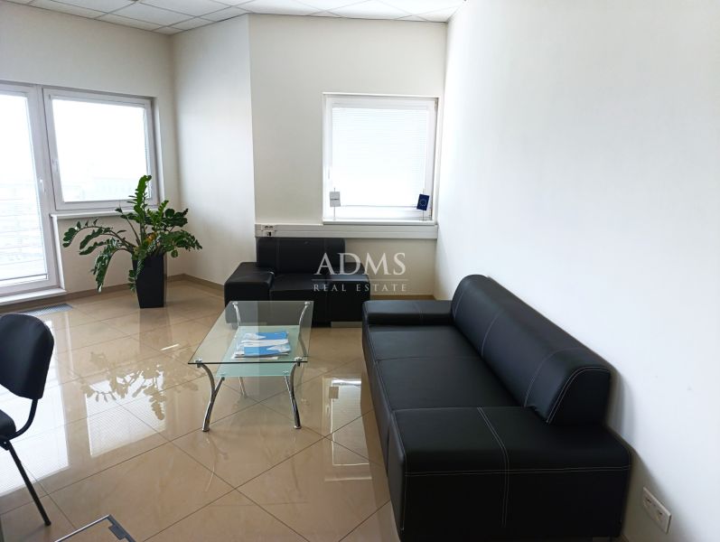 Leather sofa and glass table in an office with tiled flooring.