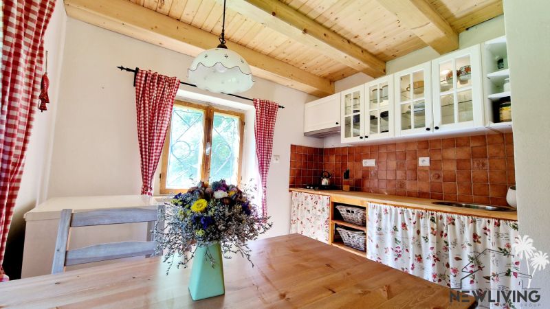 A kitchen in a cottage with a wooden ceiling, a floor with a wooden decor, flowers on the table.