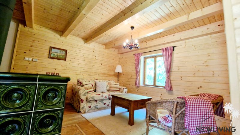 Interior of a cabin with wooden decor, a comfortable couch, and a tiled stove.