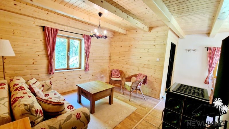 Living area in a cabin with a wooden decor floor, upholstered sofa, and wicker chairs.