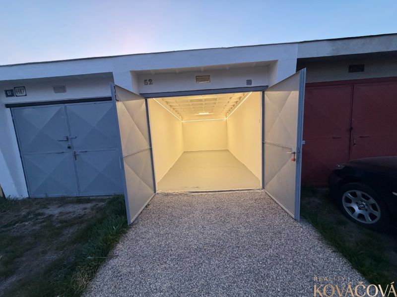 Open garages on Bezručova Street in Trenčín with concrete floors and white walls.