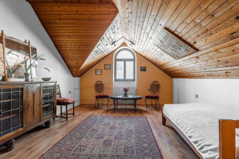 Attic room of a cottage with a wooden ceiling, antique furniture, and a floor with a wooden decor.