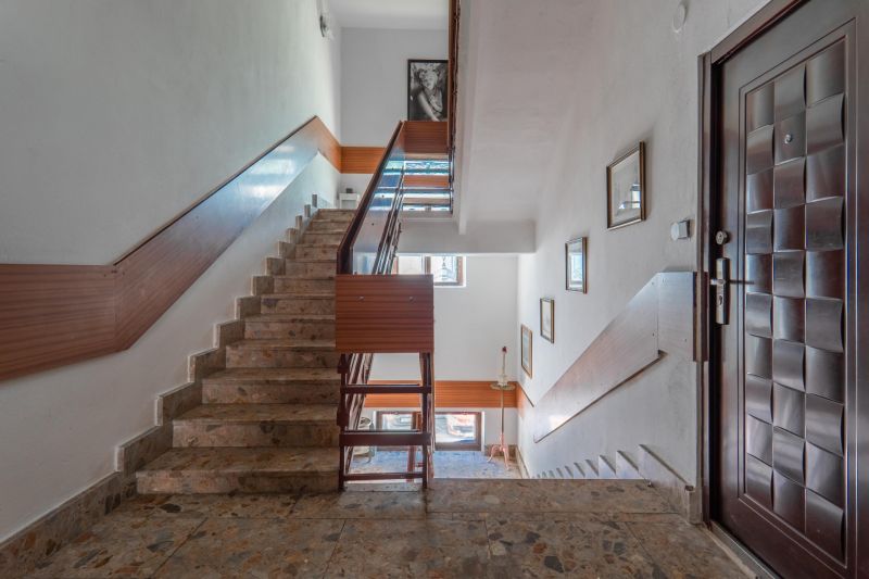 A cottage with a staircase with wooden slats and pictures on the walls.